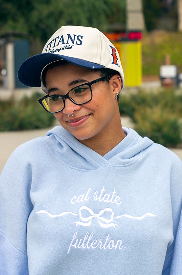 Student wearing a light blue sweatshirt and ponyflow cap.