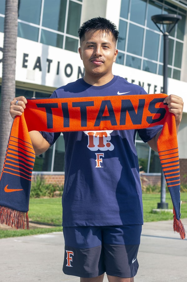 A student holding a Titans skarf in front of the TSU.
